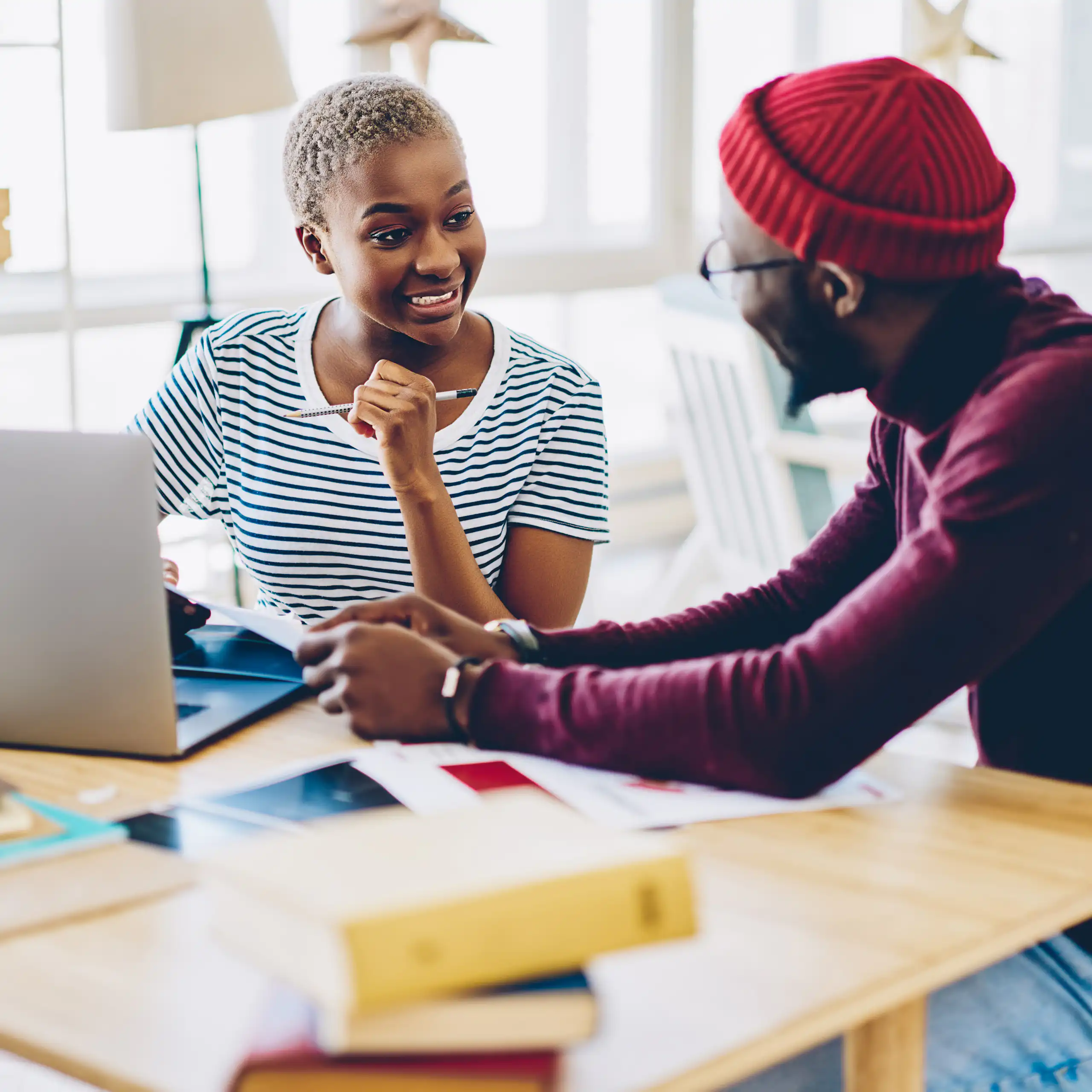Two people talking at desk with laptop