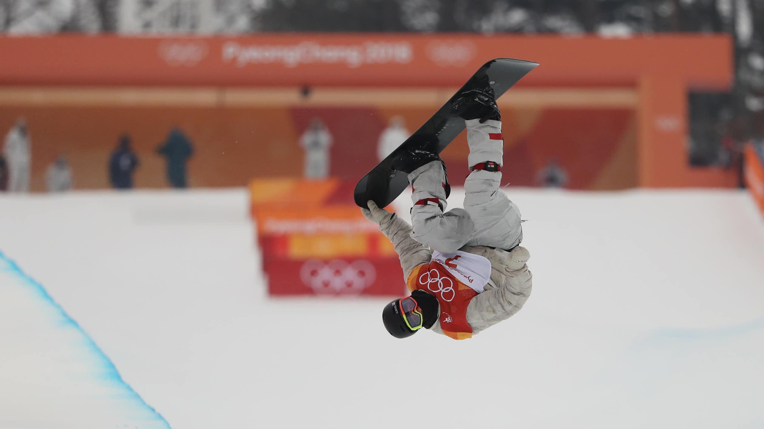 Un snowboarder fait une figure