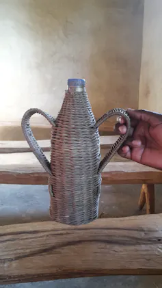 A water bottle with a cooling cover made from reeds wrapped around the bottle