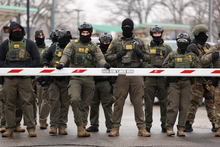 A line of people in military outfits, wearing masks and helmets.
