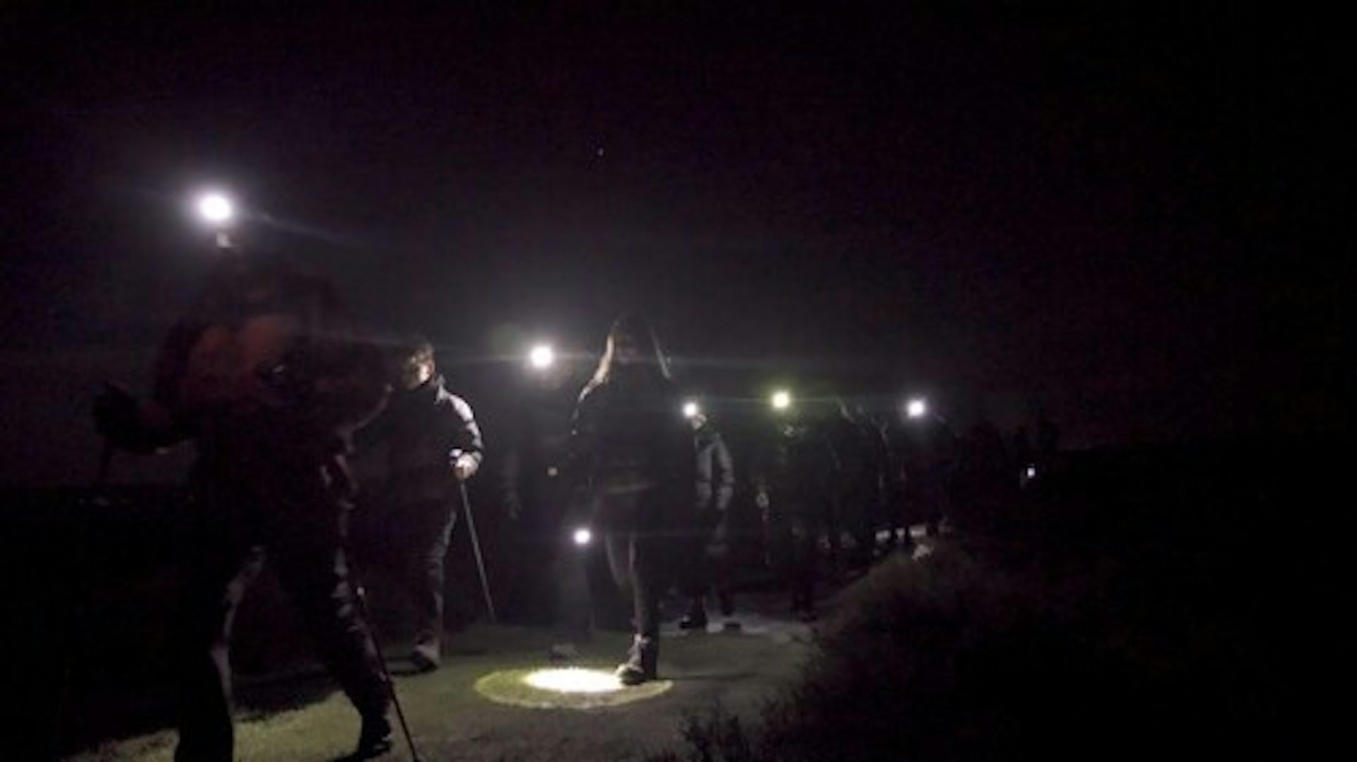 People in the dark walking with head torches during a dark sky event.