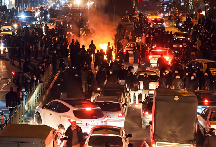 A group of people are seen by a fire.
