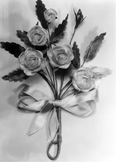 A pin with flowers, leaves and a bow.