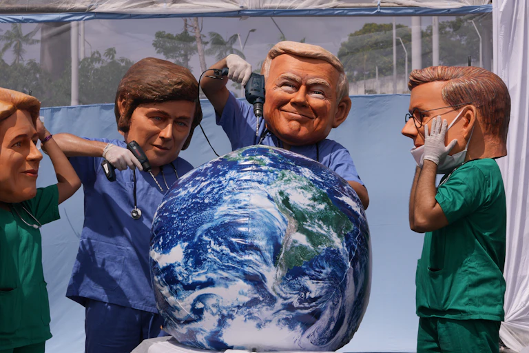 People wearing large masks bearing the likeness of donald trump and javier milei drill into a display of the planet with power drills