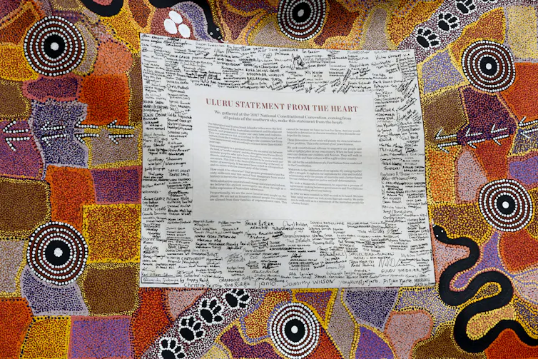 A short body of text surrounded by signatures, surrounded by colourful Indigenous art