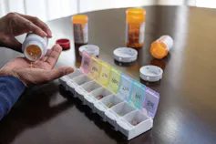 Person organizing sorting their pills at a wood table.
