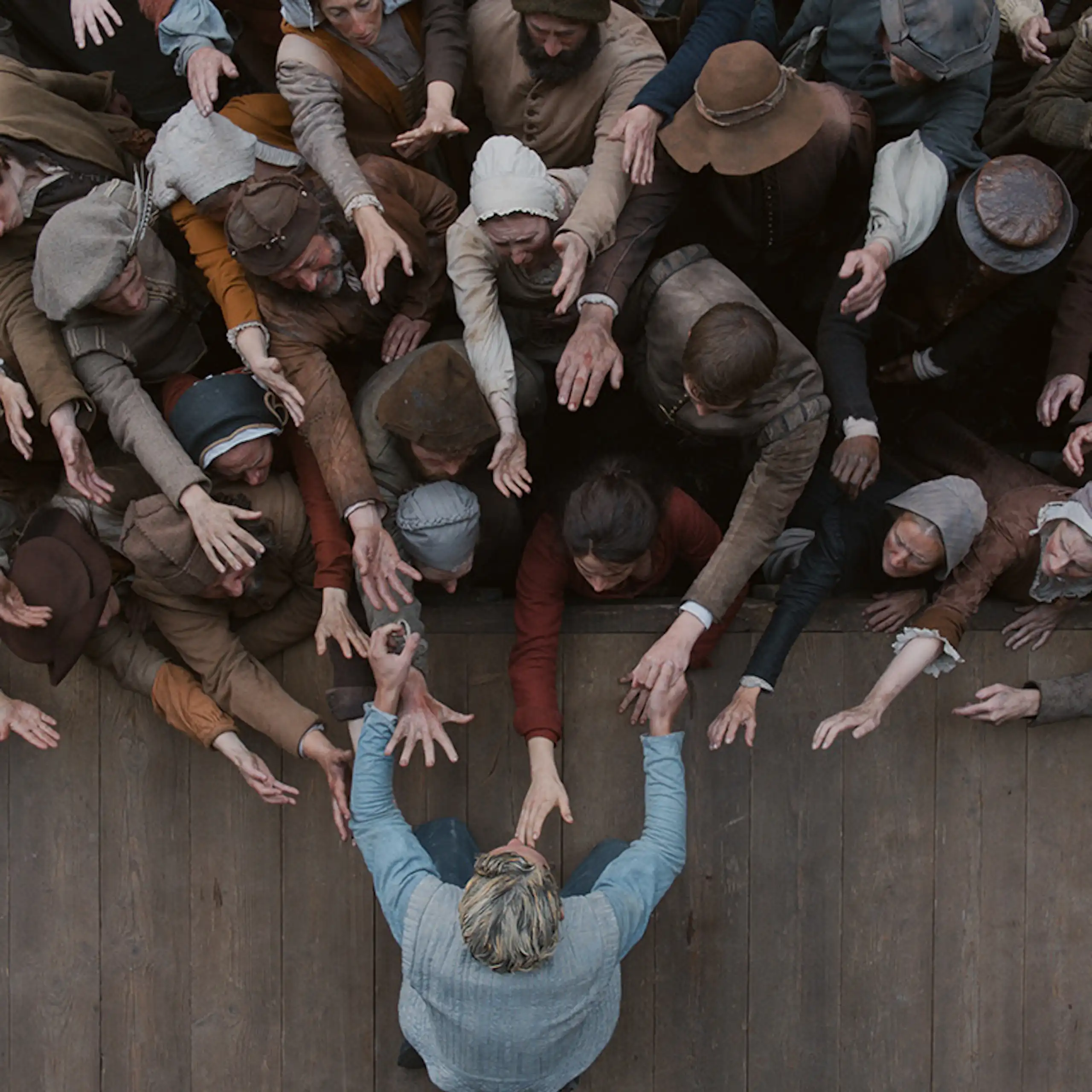 Un hombre en un escenario extiende la mano para tocar al público.