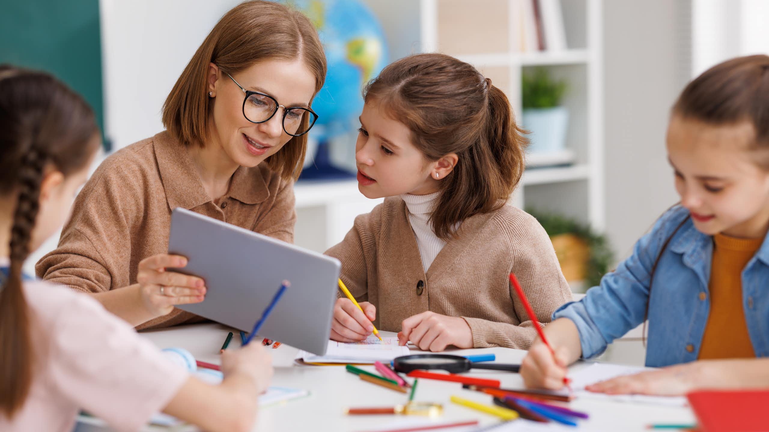 Una professora ensenya una tauleta a una alumna.