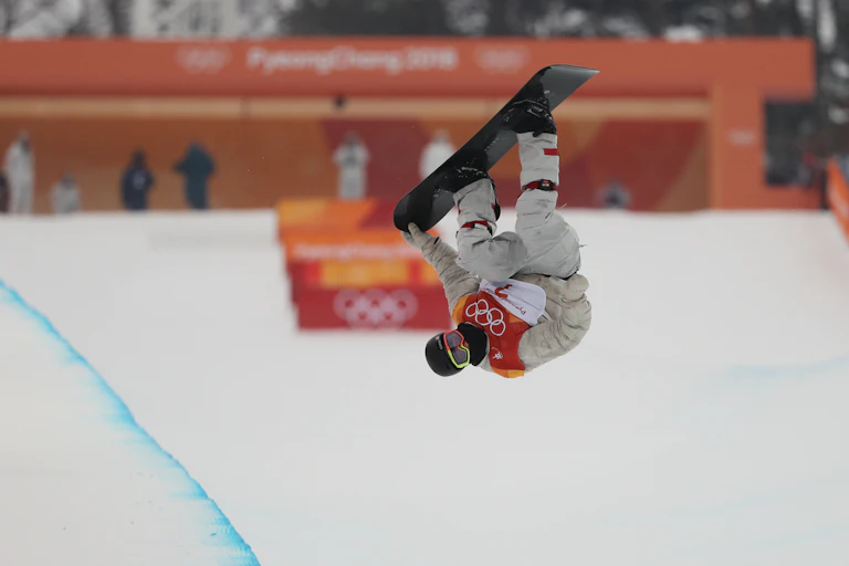 An Olympic snowboard rider performs a rotation.