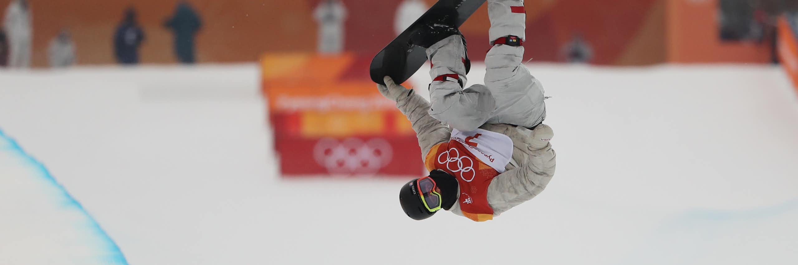 An Olympic snowboard rider performs a rotation.