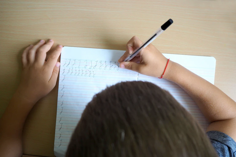 Un niño escribiendo visto desde arriba.