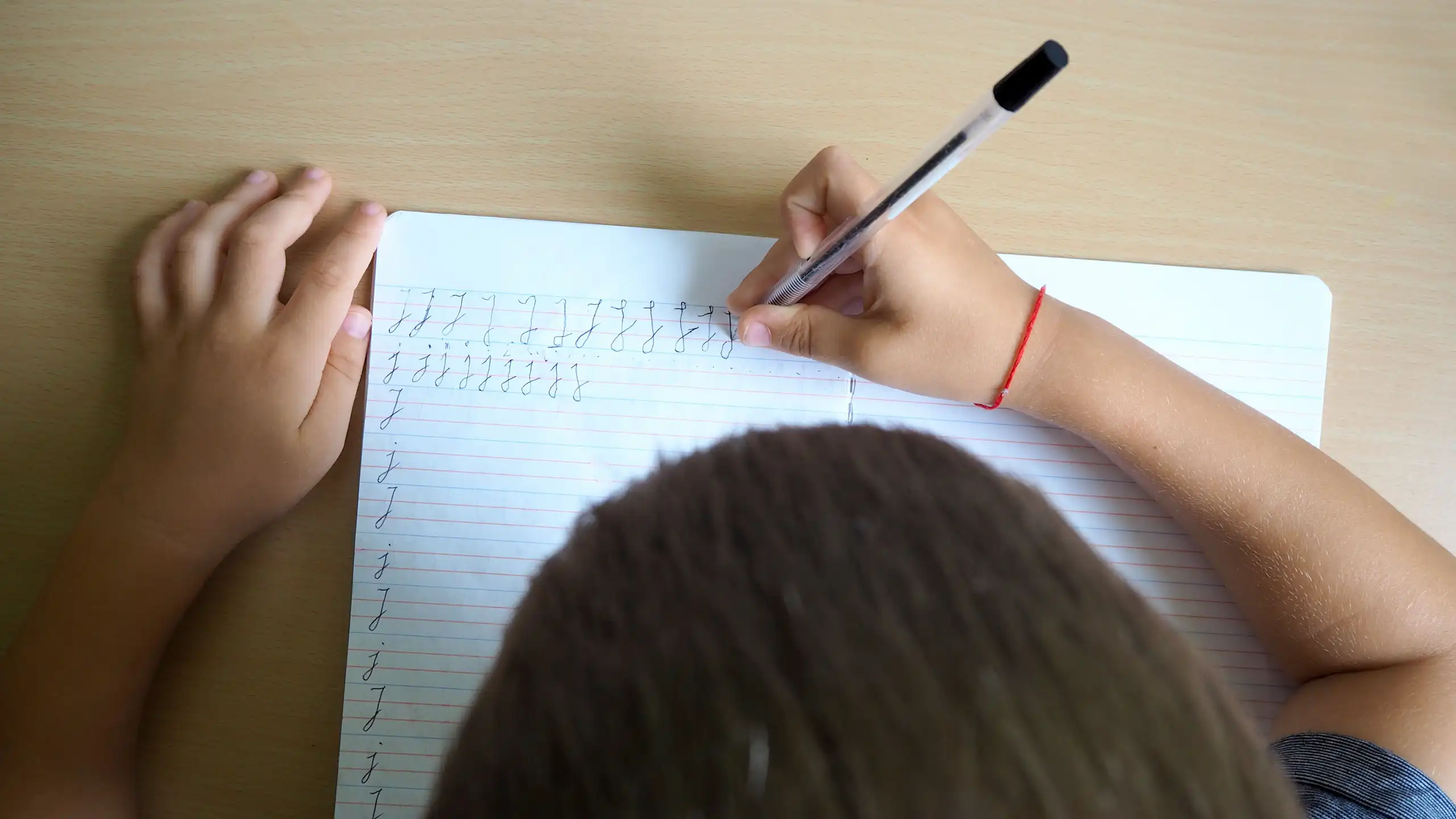 Un niño escribiendo visto desde arriba.
