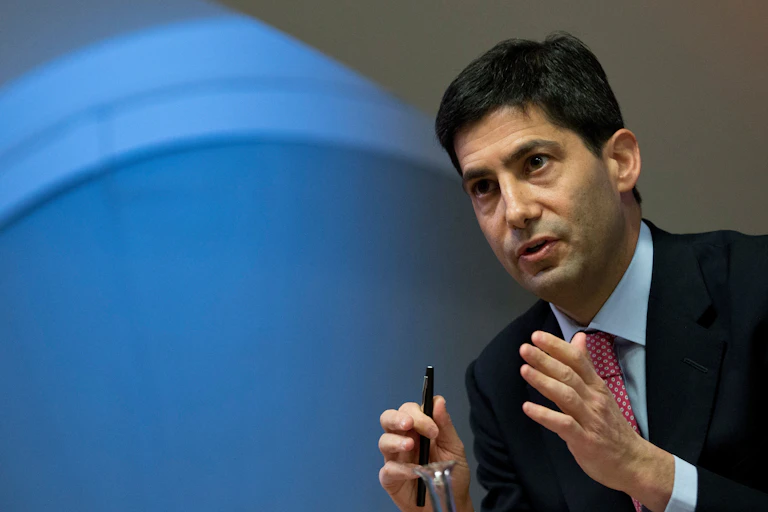 A man in a suit gestures with his hands while talking.