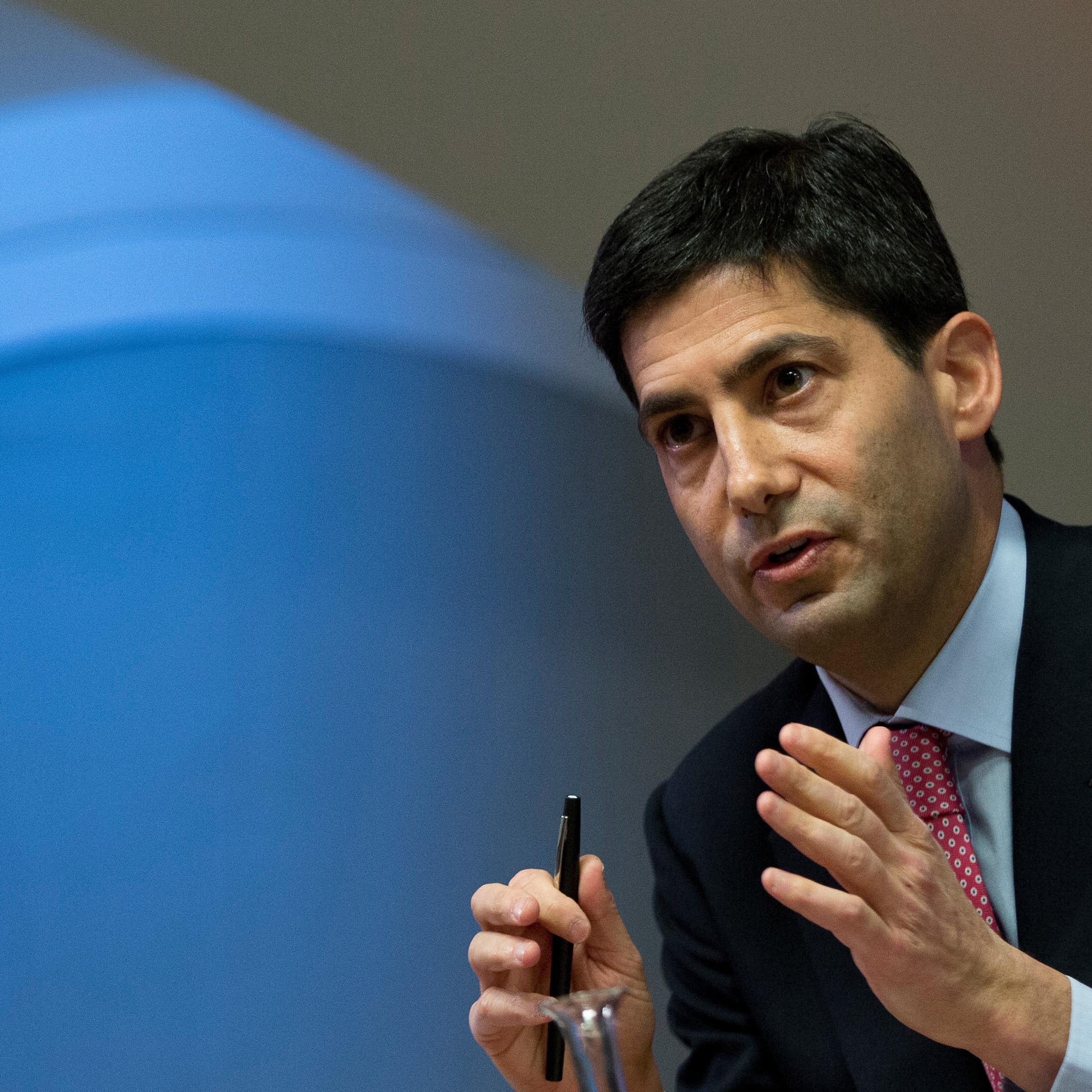 A man in a suit gestures with his hands while talking.