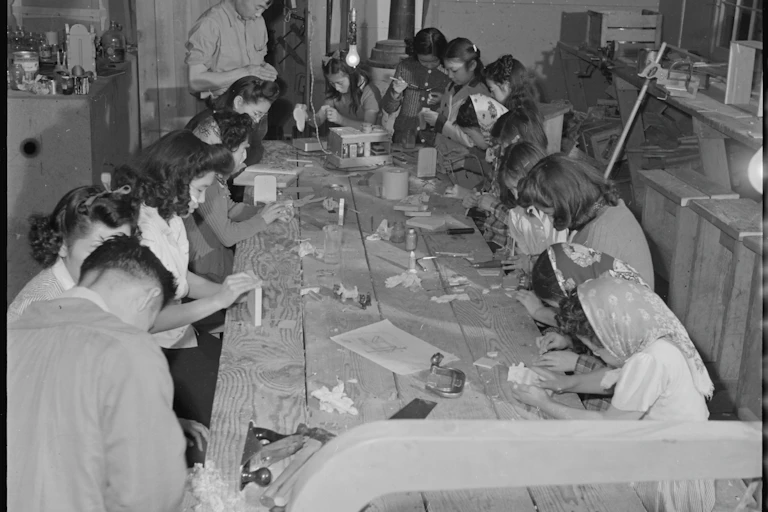 People sit around a table looking down at items they are handling.