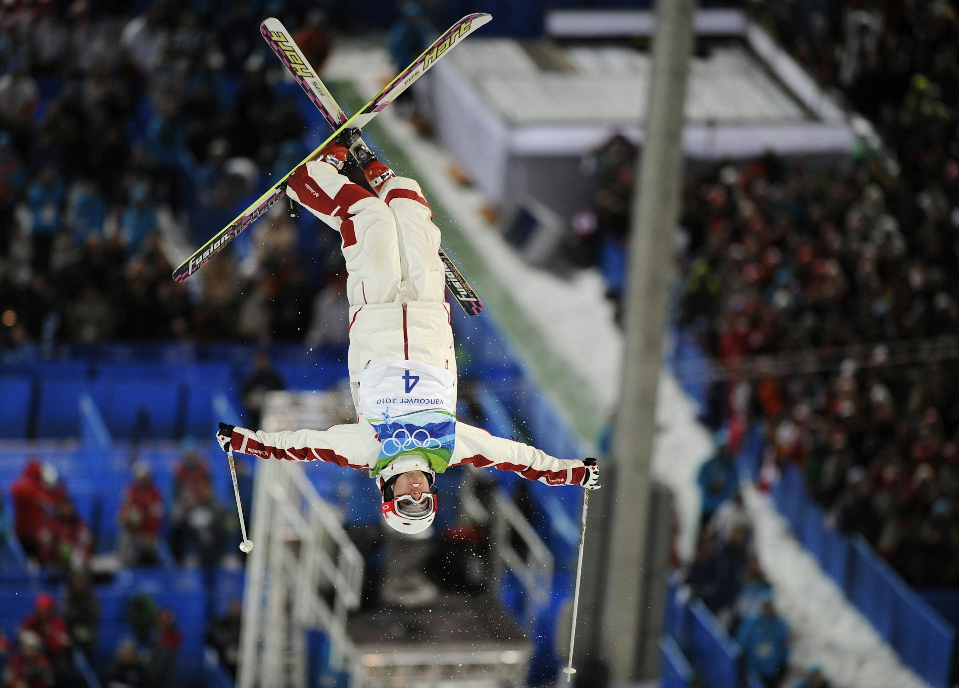 Un hombre con esquís cuelga boca abajo en el aire en mitad de un giro.