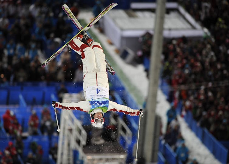 Estas son las esperanzas de medalla de Canadá en los Juegos Olímpicos de Invierno de 2026, desde el hockey hasta el esquí estilo libre 2 Un hombre con esquís cuelga boca abajo en el aire en mitad de un giro.
