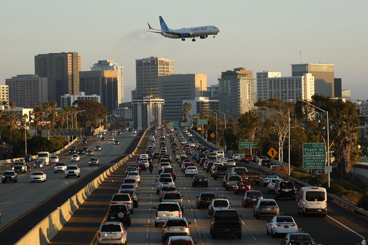 An airplane flying over a packed highway with San Diego in the background.