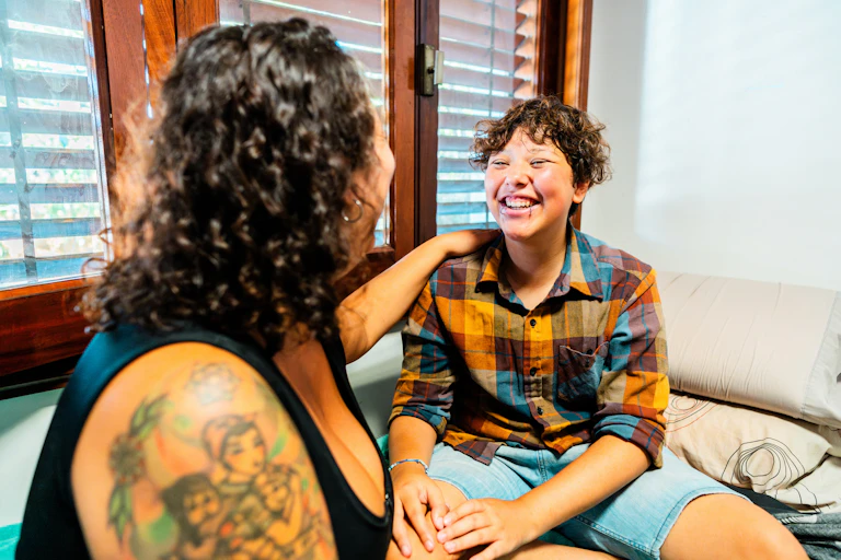A smiling trans person with their mum.