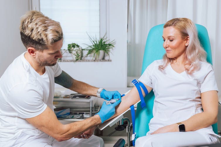 A woman has her blood taken by a male nurse or doctor.
