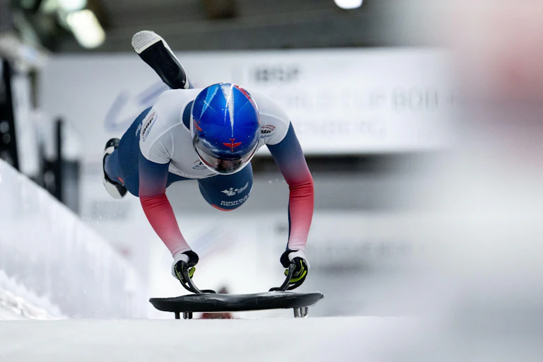Amelia Coltman from Great Britain jumps aboard her skeleton at the end of the sprint start.