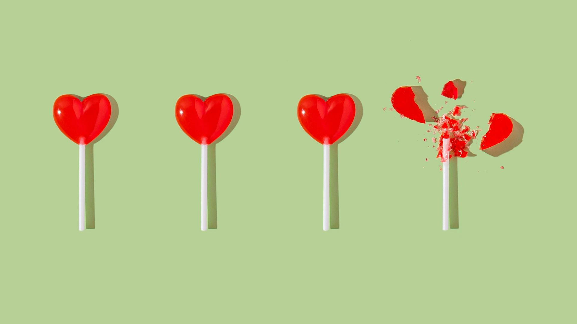 Four heart-shaped lollipops; one is broken.