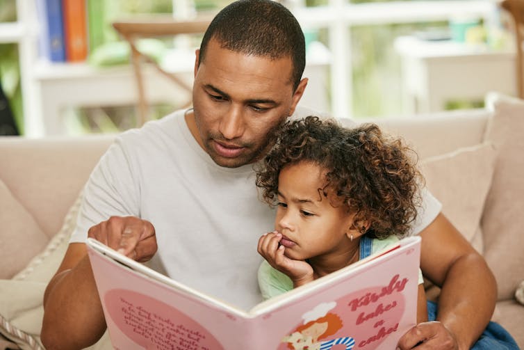 Father and daughter looking at book