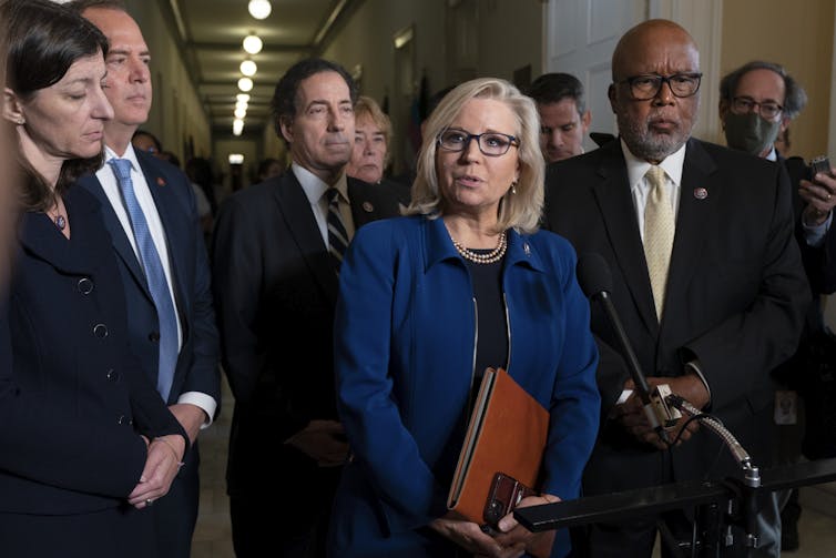 Liz Cheney, a former House Republican, speaks at a microphone alongside other Jan. 6 investigators.