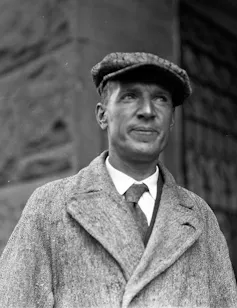 A man in an overcoat with white shirt and tie.