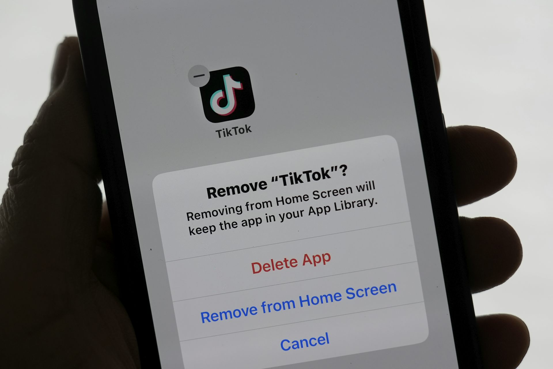 A person's hand holding a phone displaying a notice on deleting tiktok