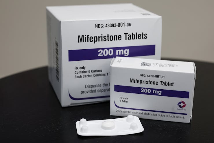 Packages of mifepristone tablets are displayed.