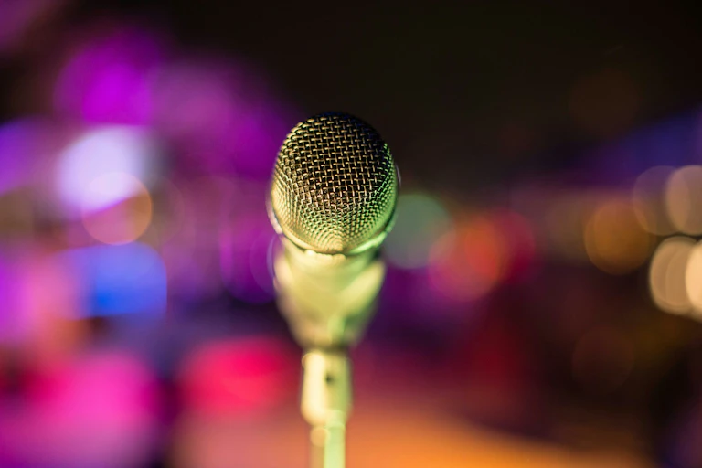 Microphone on stand on stage, audience blurred