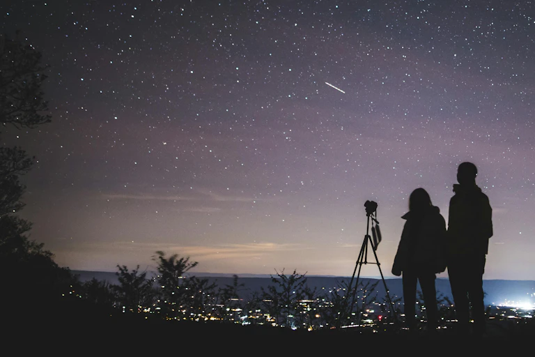 Silhouette of two people stargazing.