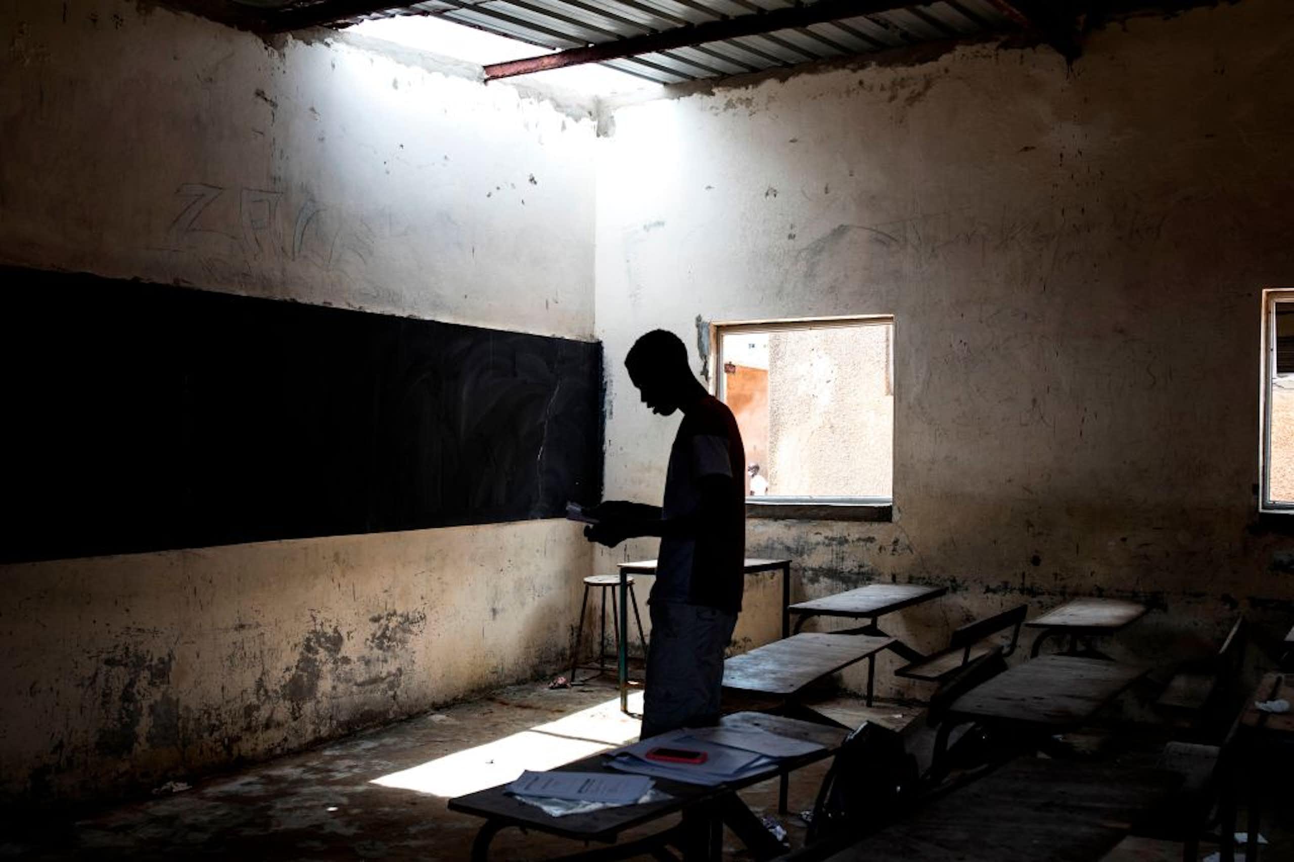 A person standing in a dilapidated classroom