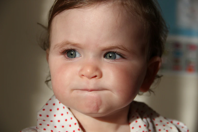Bébé aux yeux bleus faisant la moue.