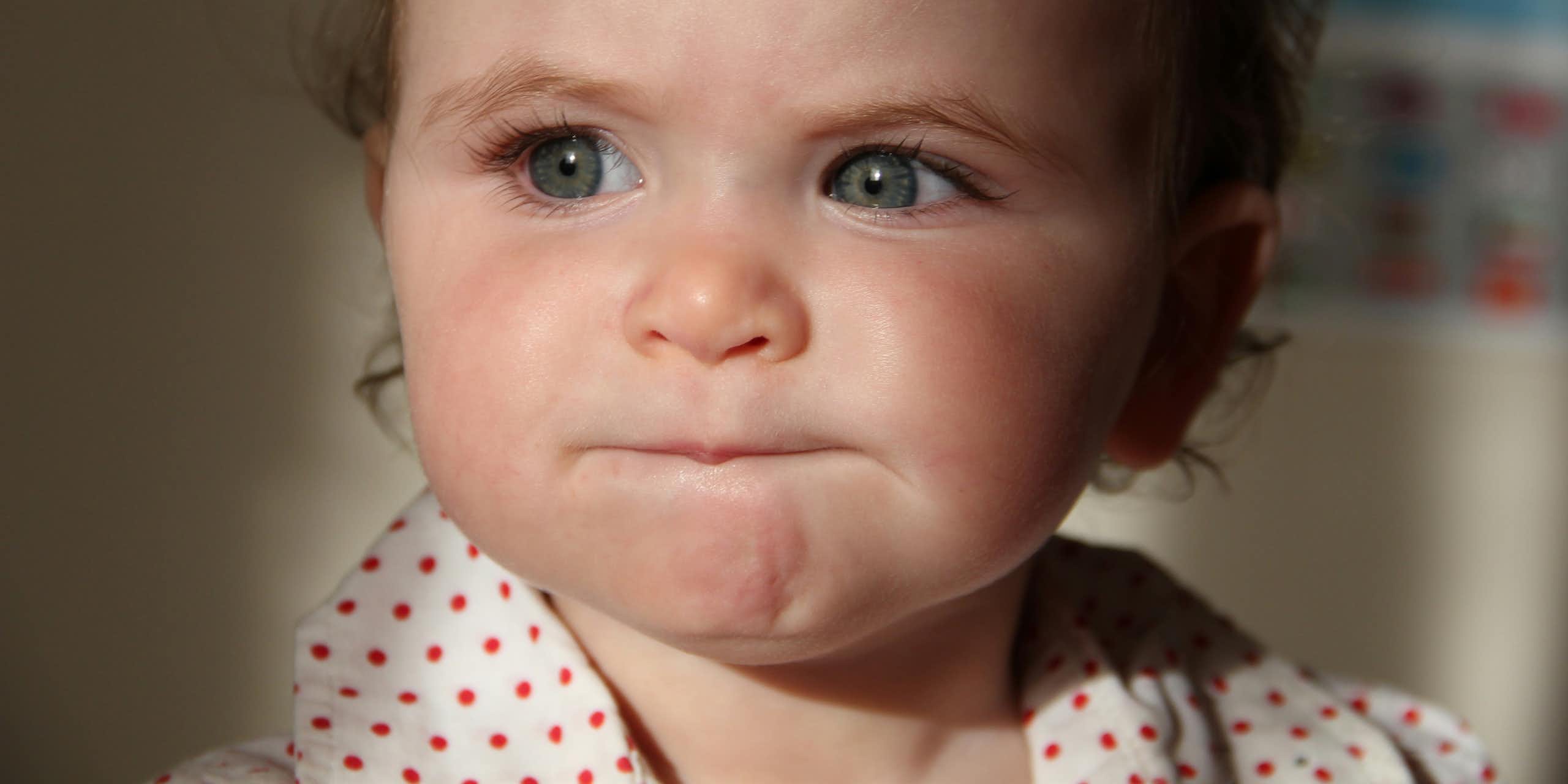 Bébé aux yeux bleus faisant la moue.
