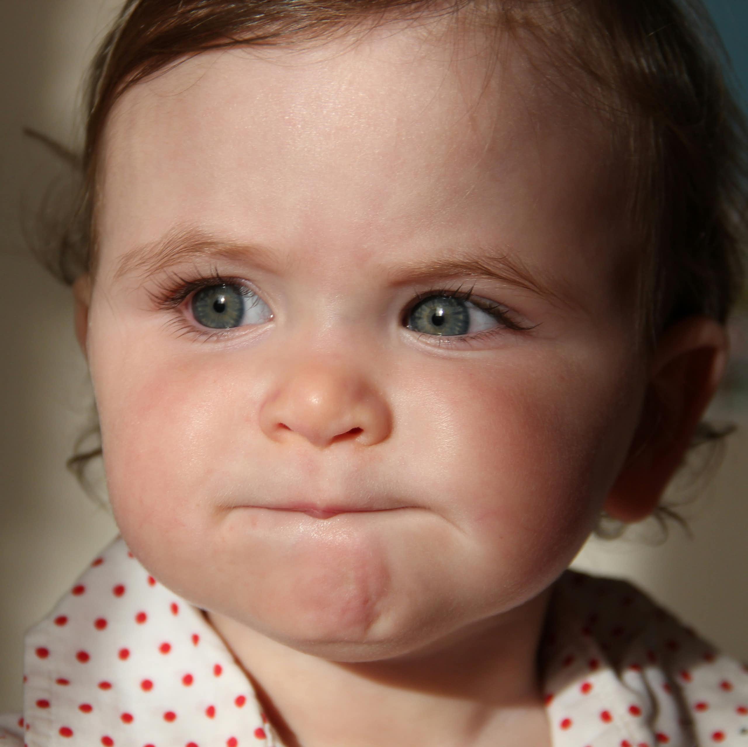 Bébé aux yeux bleus faisant la moue.