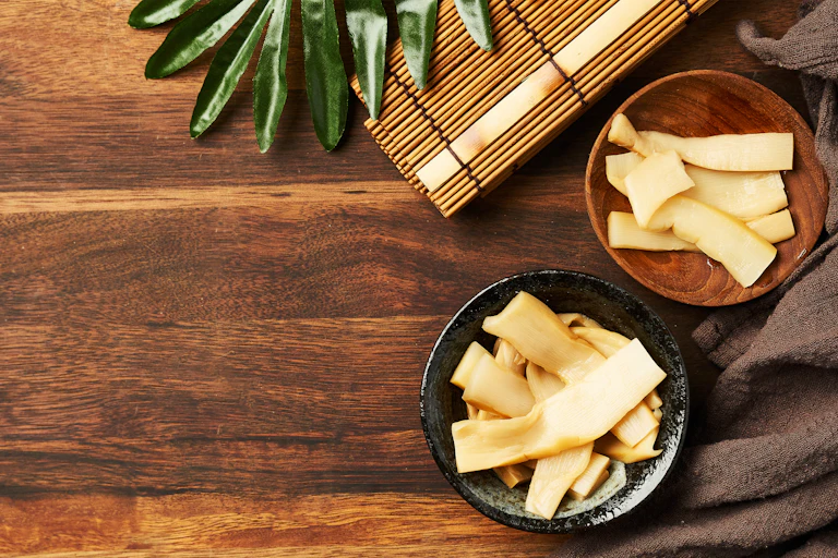 Bamboo shoots in two bowls on a wooden counter top.