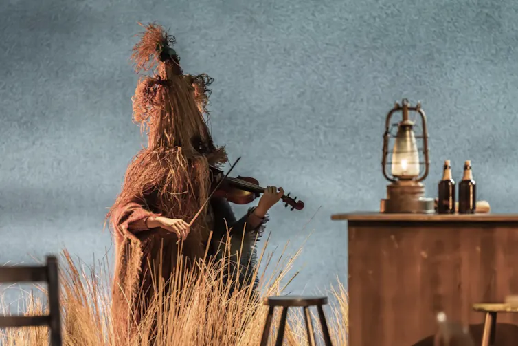 A character onstage wearing a straw mumming costume.