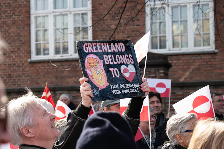 Des manifestants anti-Trump tiennent des pancartes avec le drapeau du Groenland