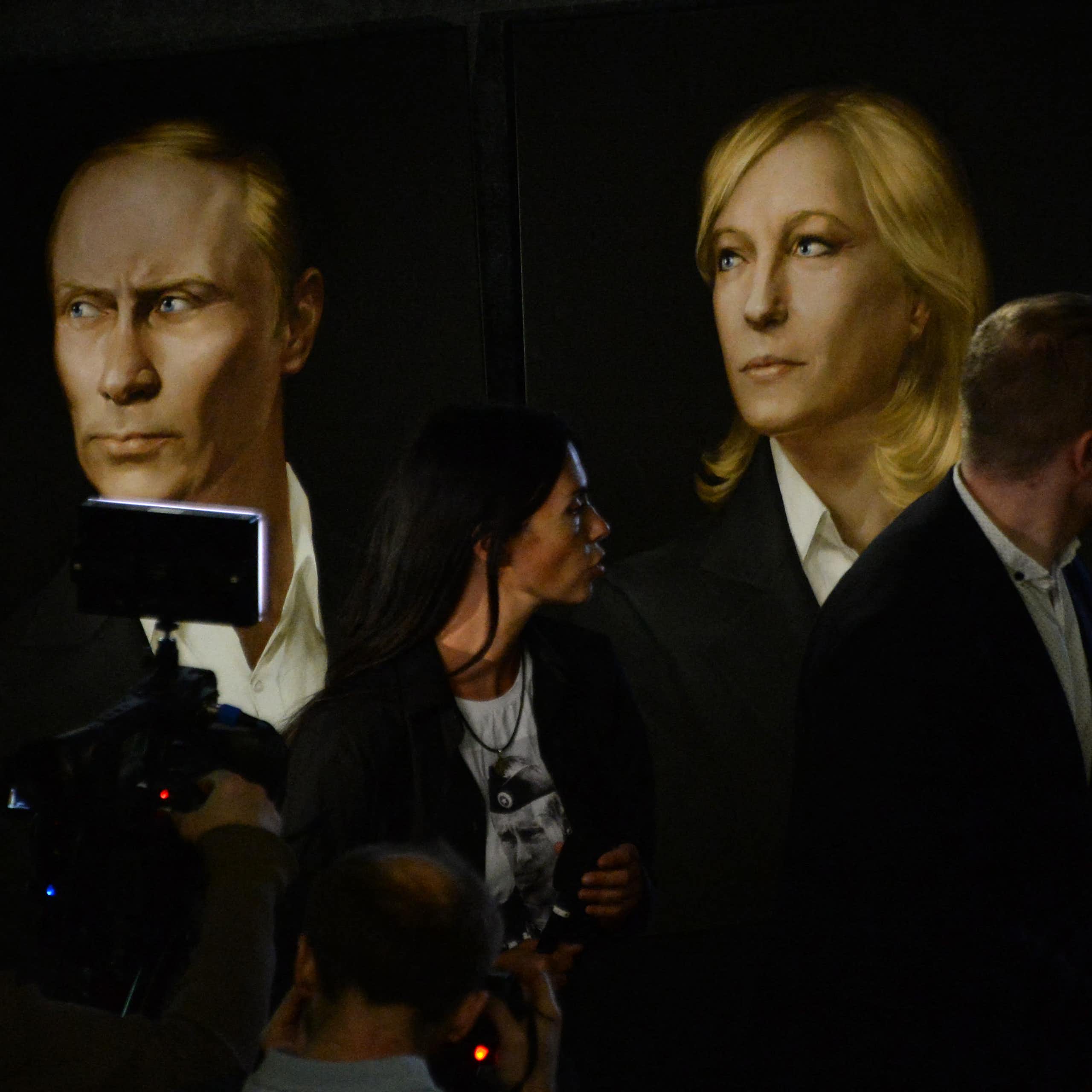 trois portraits (Poutine, Marine Le Pen et Trump) et des personnes qui les regardent.