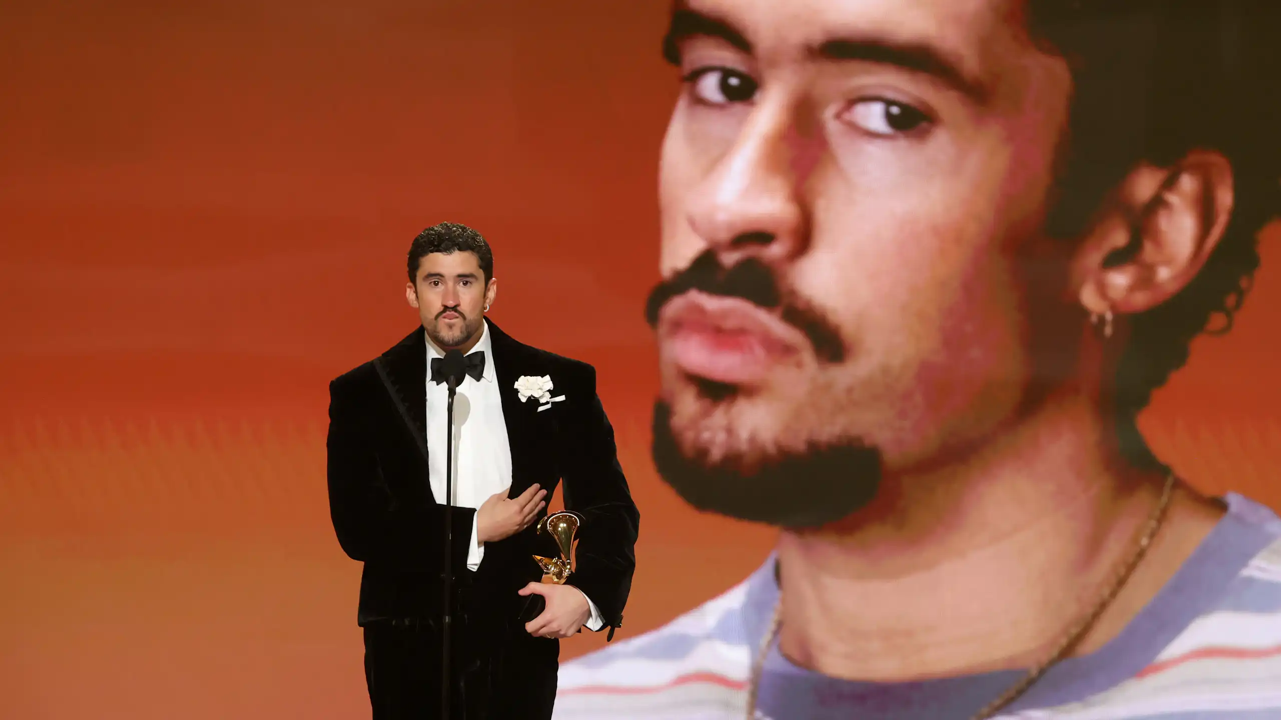 Un hombre sostiene un premio mientras habla detrás de un micrófono.