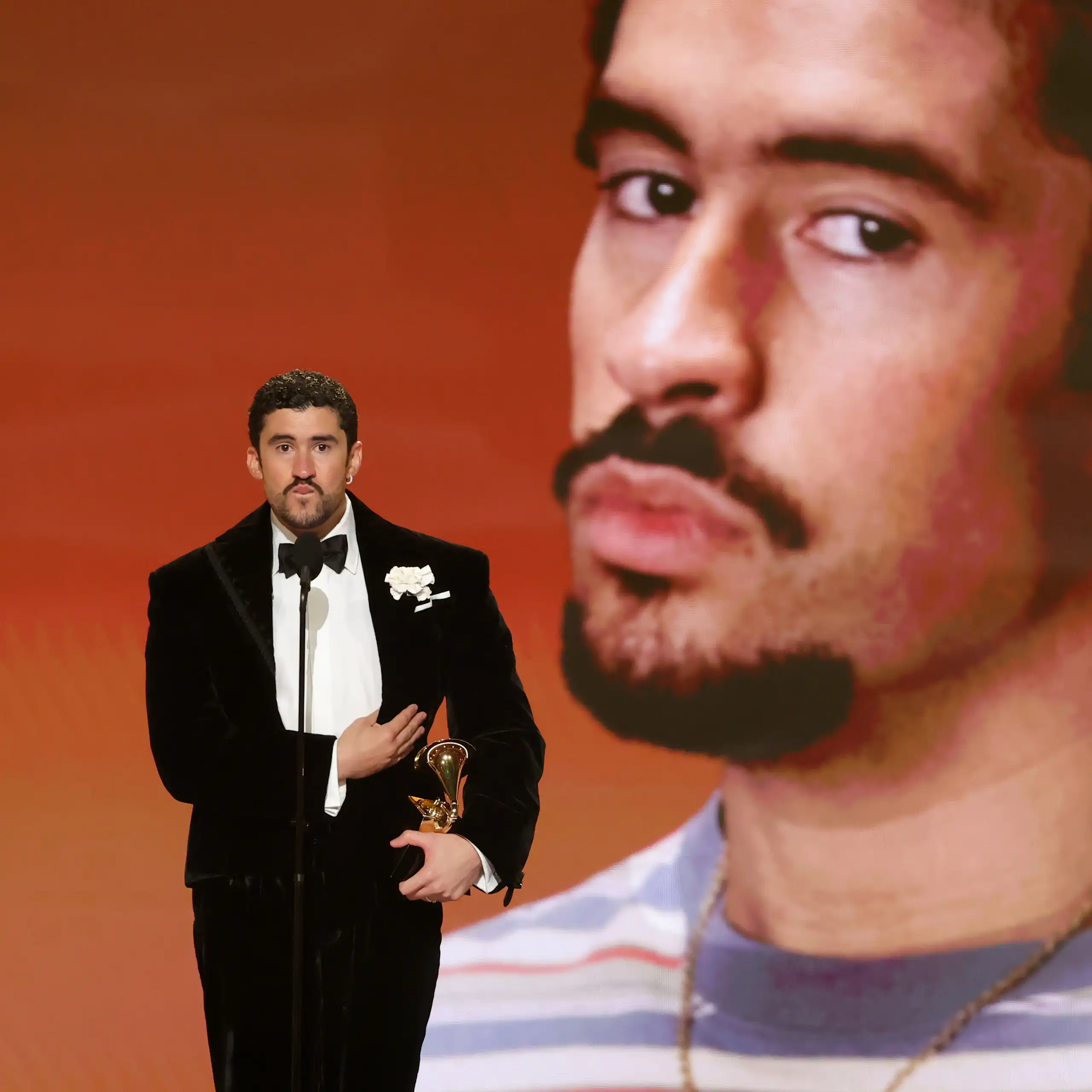 Un hombre sostiene un premio mientras habla detrás de un micrófono.