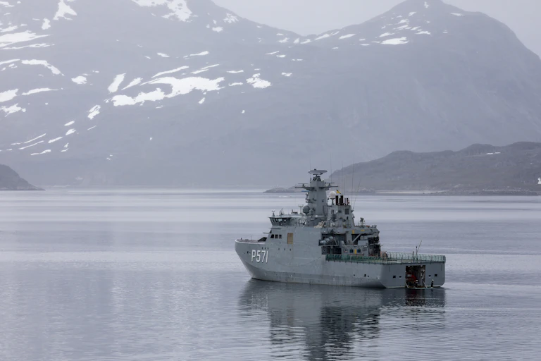 Un barco navega hacia un paisaje de montañas nevadas.
