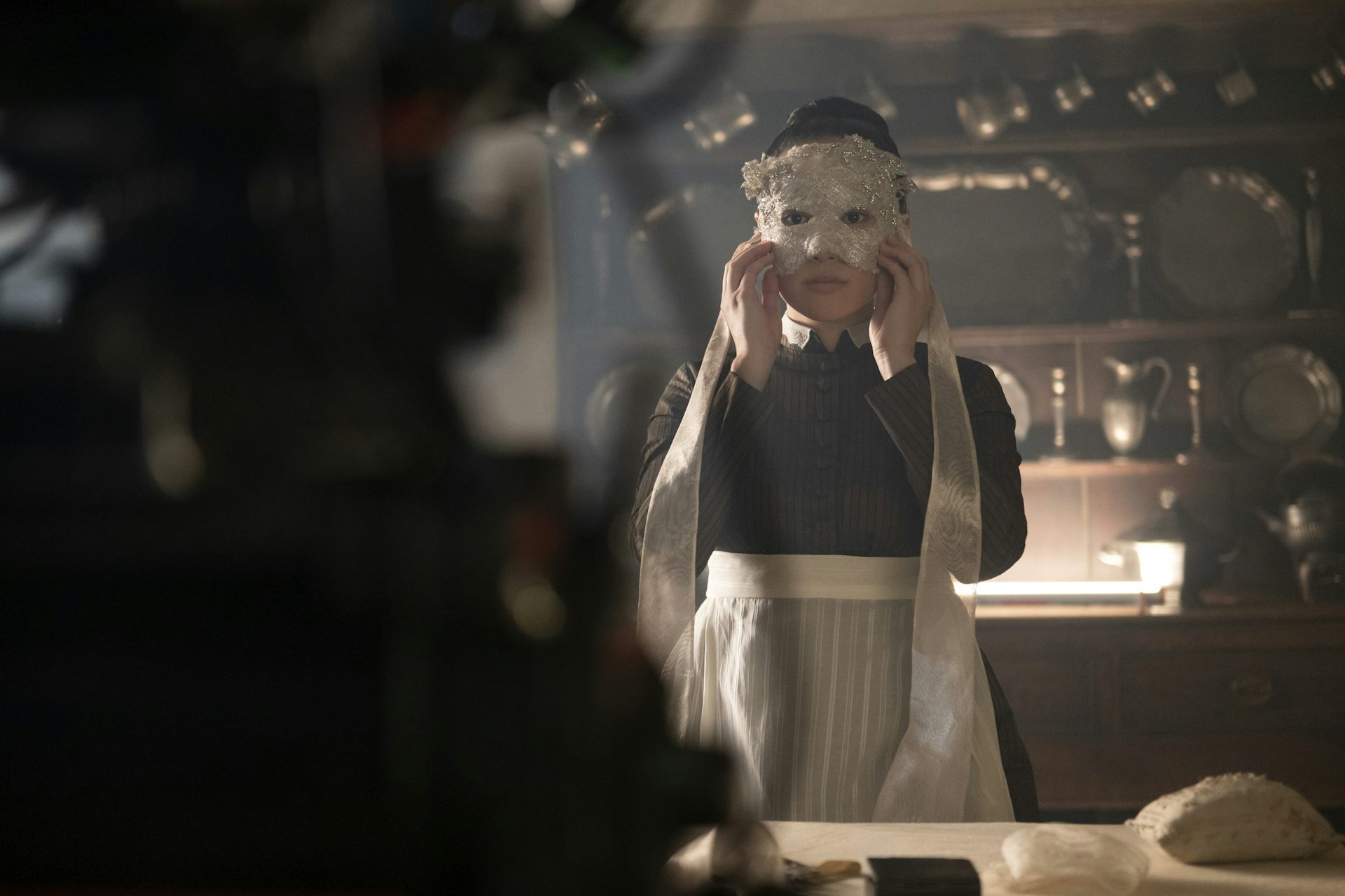 Maid Sophie Baek holding a mask to her face 