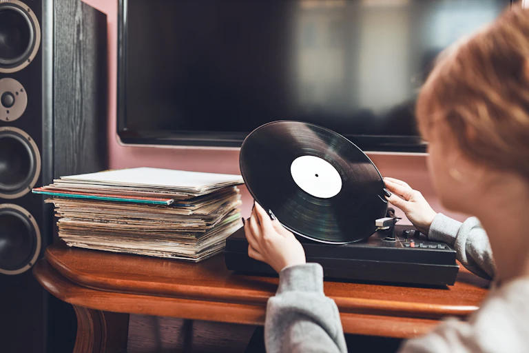 Una mujer observa un disco de vinilo frente a un tocadiscos.