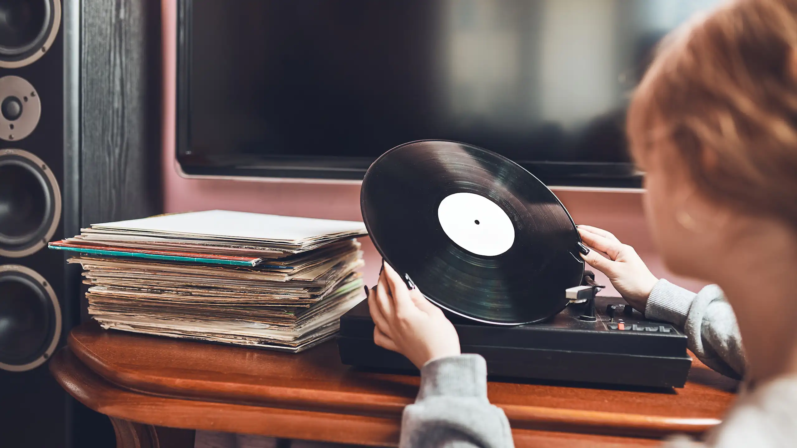 Una mujer observa un disco de vinilo frente a un tocadiscos.