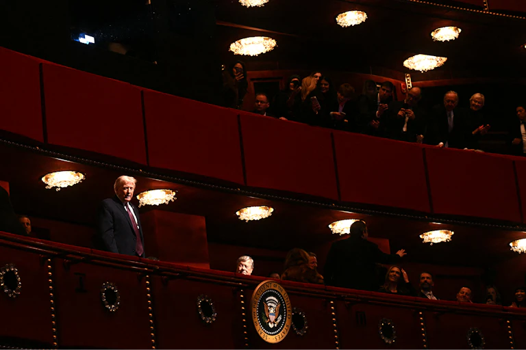 President Trump is seen standing in a box seat at a fancy theater.