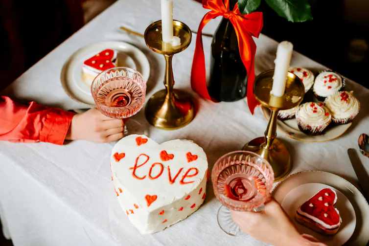A Valentine's Day meal in a restaurant with cake and drinks on the table between a couple.