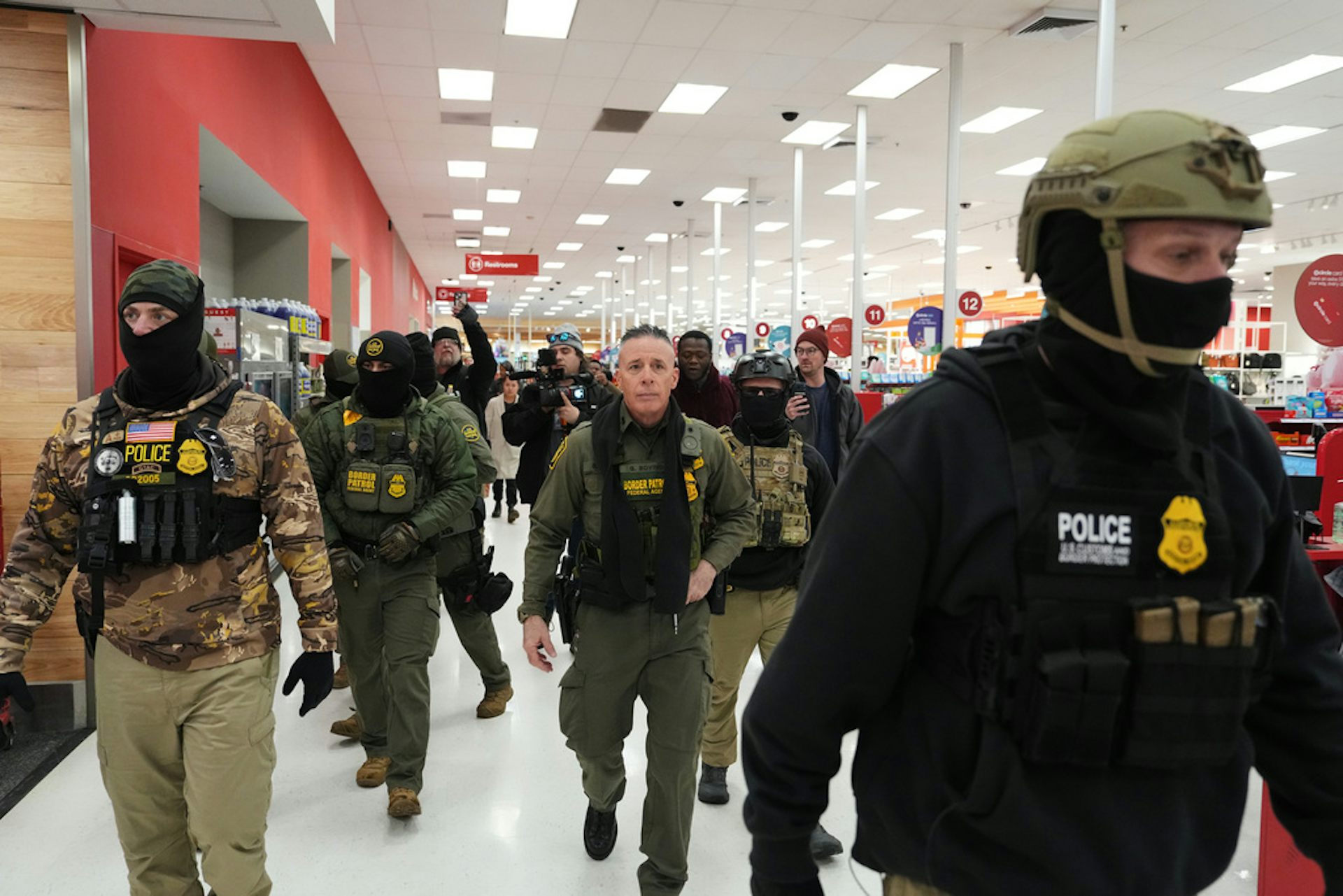 Men in law enforcement garb walk through a store.